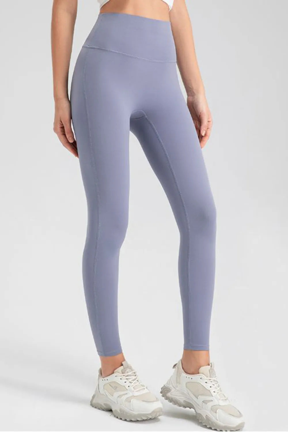 Model wears lavender high-waist skinny active pants with a smooth, stretchy leggings silhouette, seamed construction, and ankle-length tapered legs.