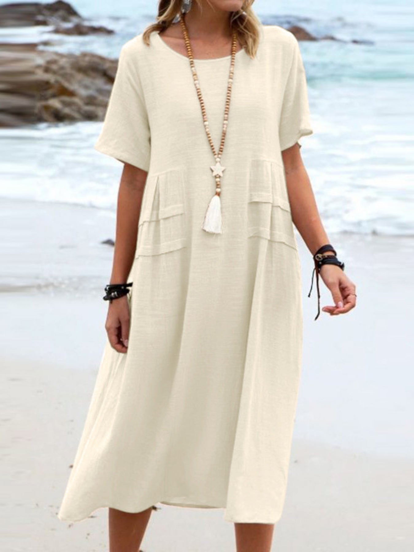 Plus size loose midi dress with short sleeves and pockets shown in cream and black by the beach