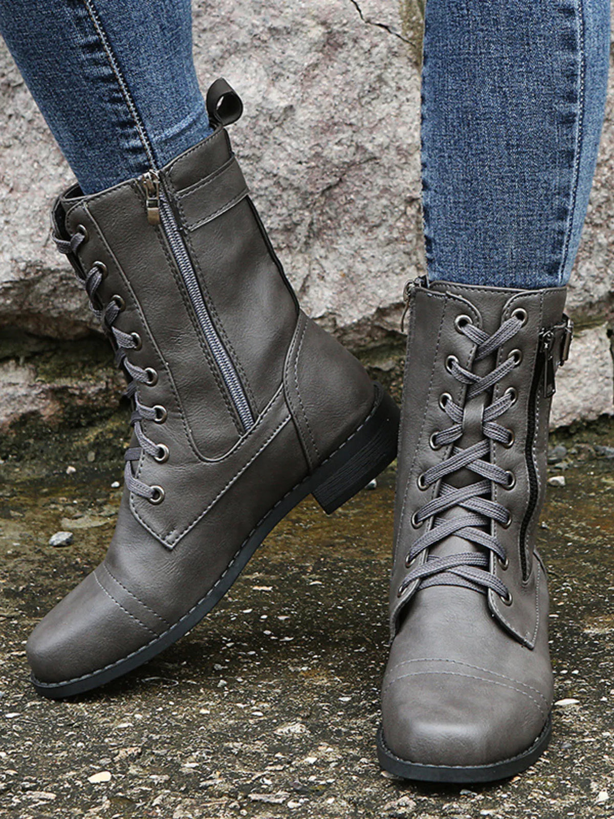 Close-up of a model wearing gray PU leather lace-up boots with side zippers, stitched panel construction, rounded toes, and low block heels.