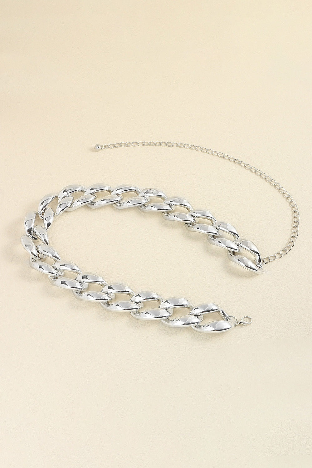Silver-tone acrylic curb chain belt featuring bold interlocking links, a 1.2-inch width, and a draped extension chain with adjustable fastening.