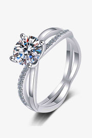 Silver 1-carat moissanite ring with a crisscross split shank, round center stone, four-prong setting, and sparkling zircon accents along the bands.
