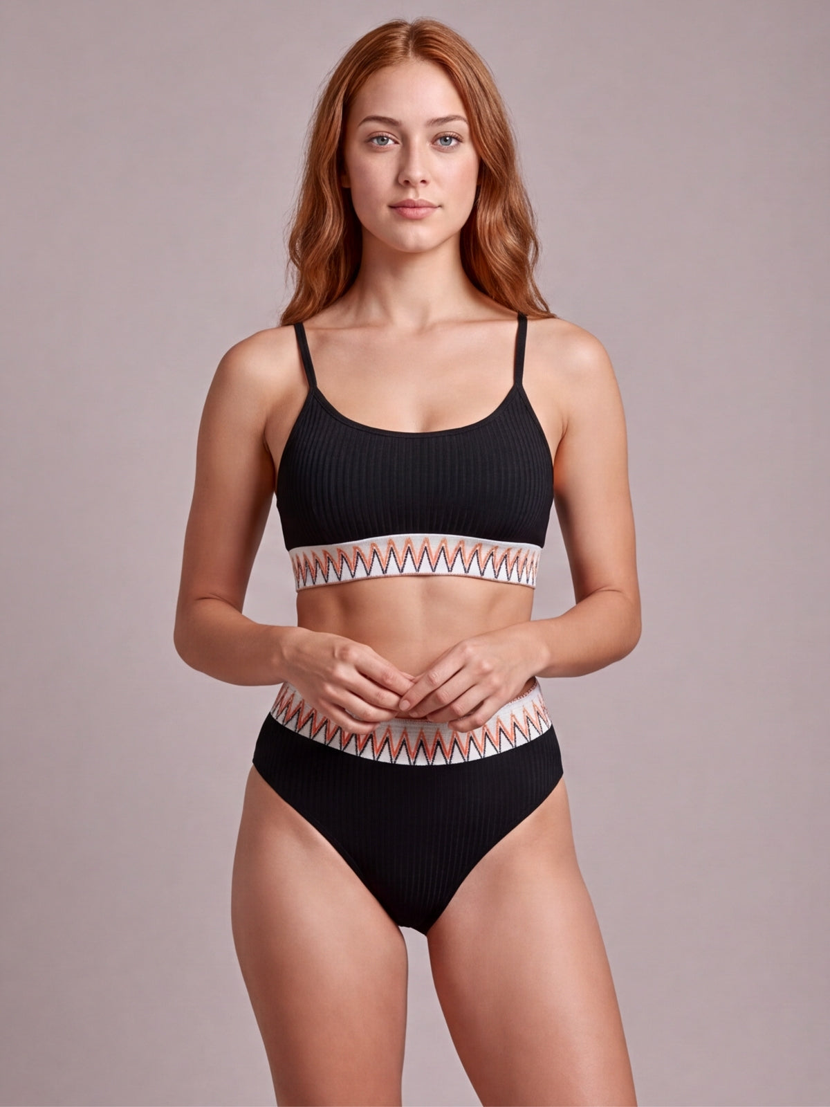 Model wearing a black textured ribbed high-waist bikini with contrast geometric banding, thin straps, scoop neckline, and moderate-coverage bottoms.