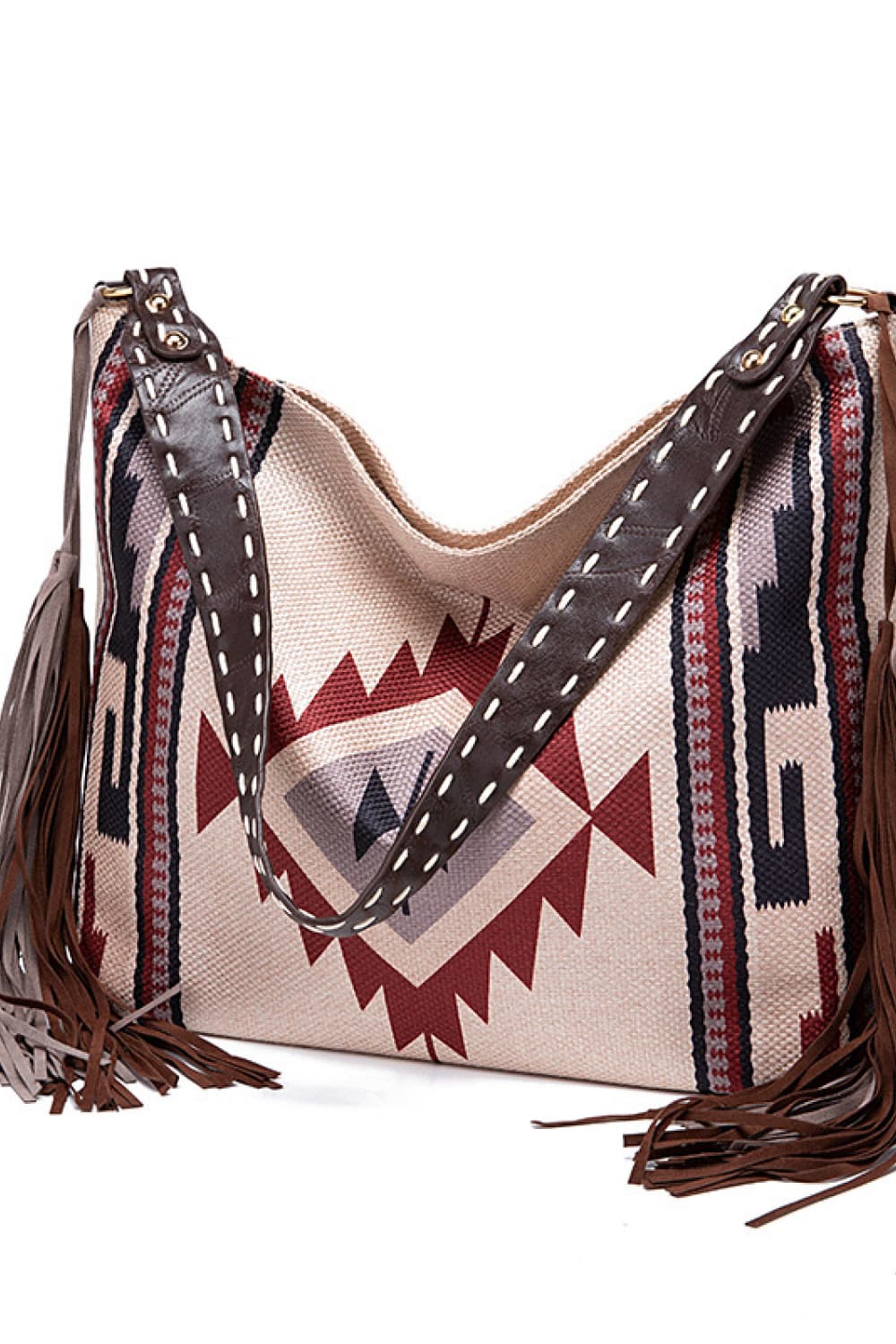 Oversized geometric canvas tote bag in beige, burgundy, navy, and brown, featuring patterned panels, stitched leather-look straps, and long fringe trim.