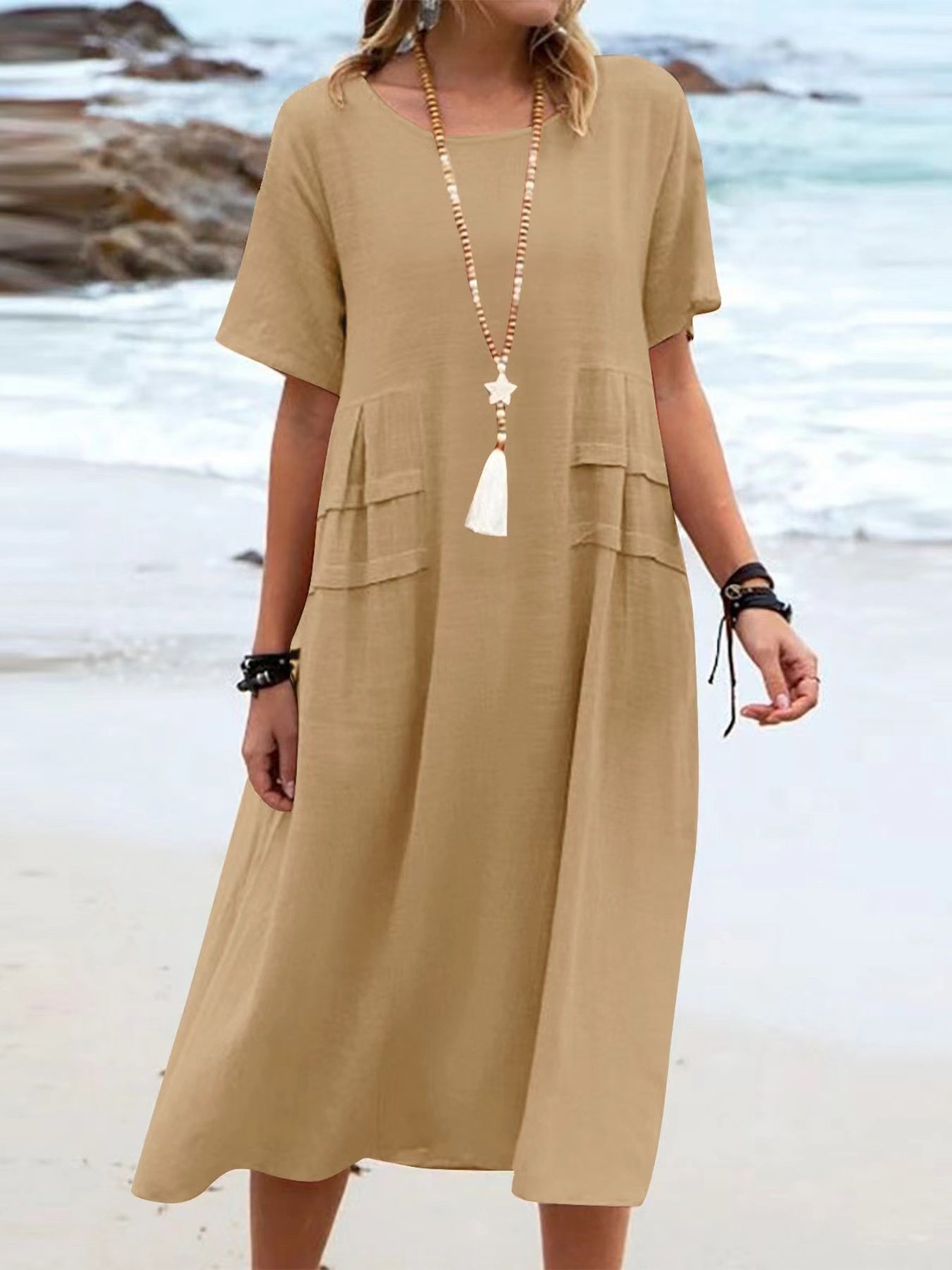 Plus size loose midi dress with short sleeves and pockets shown in cream and black by the beach
