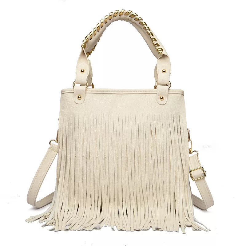 Cream medium PU leather handbag with long fringe across the front, structured tote silhouette, dual top handles with chain accents, and an adjustable shoulder strap.