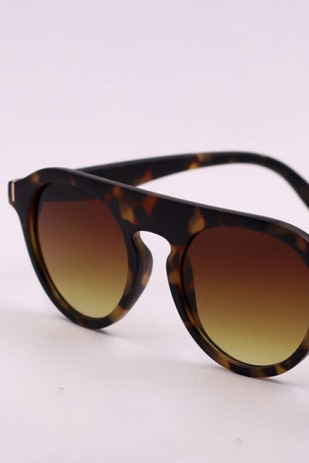 Tortoiseshell-inspired round full-rim sunglasses feature bold polycarbonate frames, softly curved temples, and warm gradient lenses fading from brown to amber.