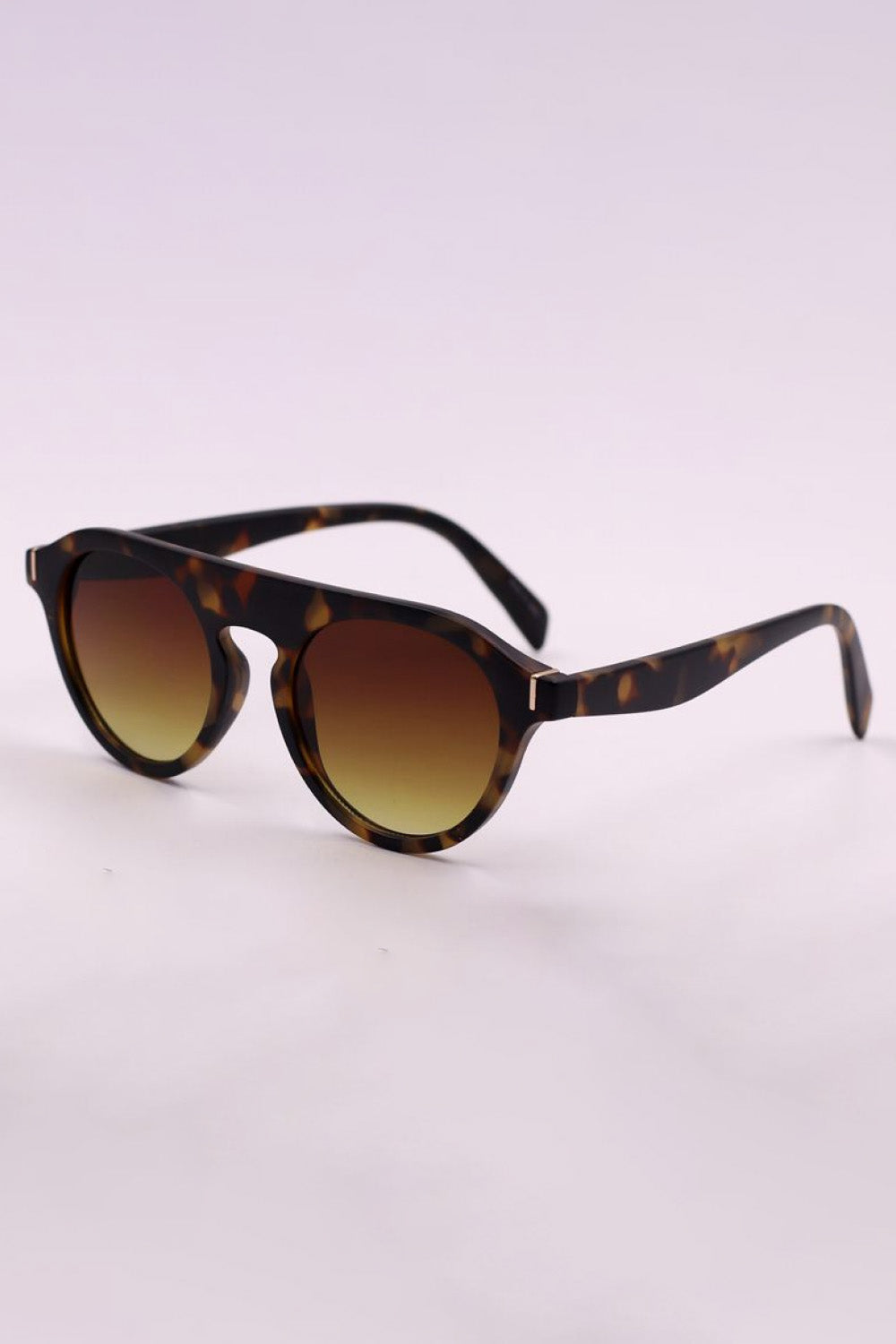 Round full-rim sunglasses in a tortoiseshell-inspired polycarbonate frame feature warm gradient lenses, softly curved temples, and a polished vintage silhouette.