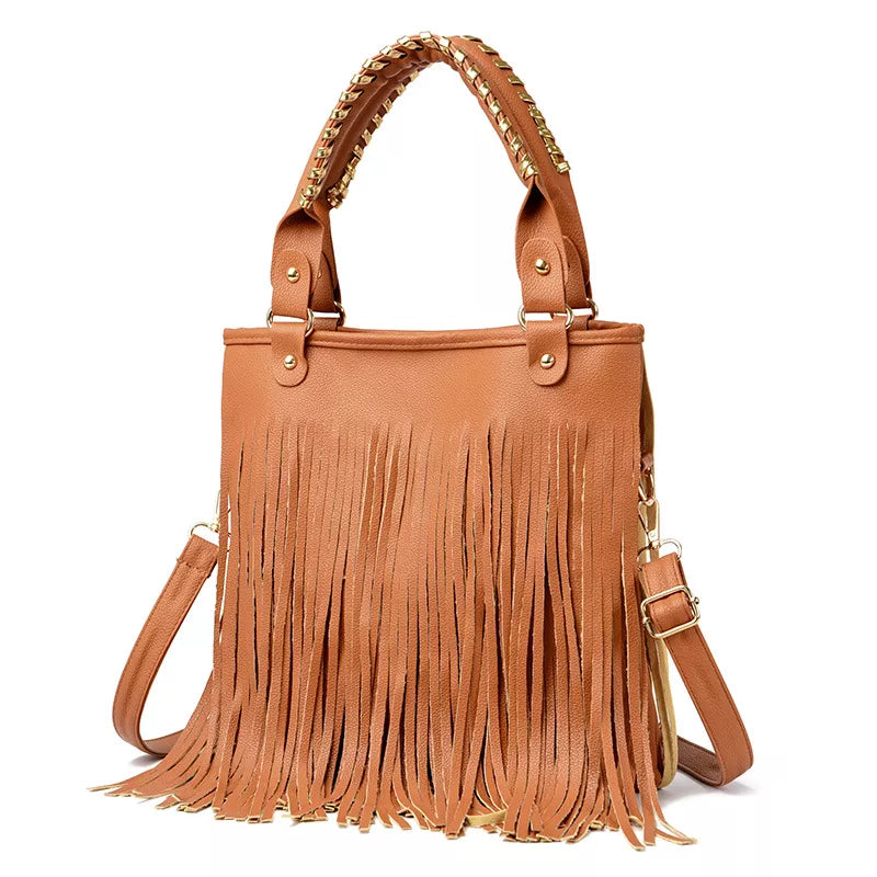 Medium tan PU leather handbag with long fringe, dual studded handles, an adjustable shoulder strap, and gold-tone hardware.