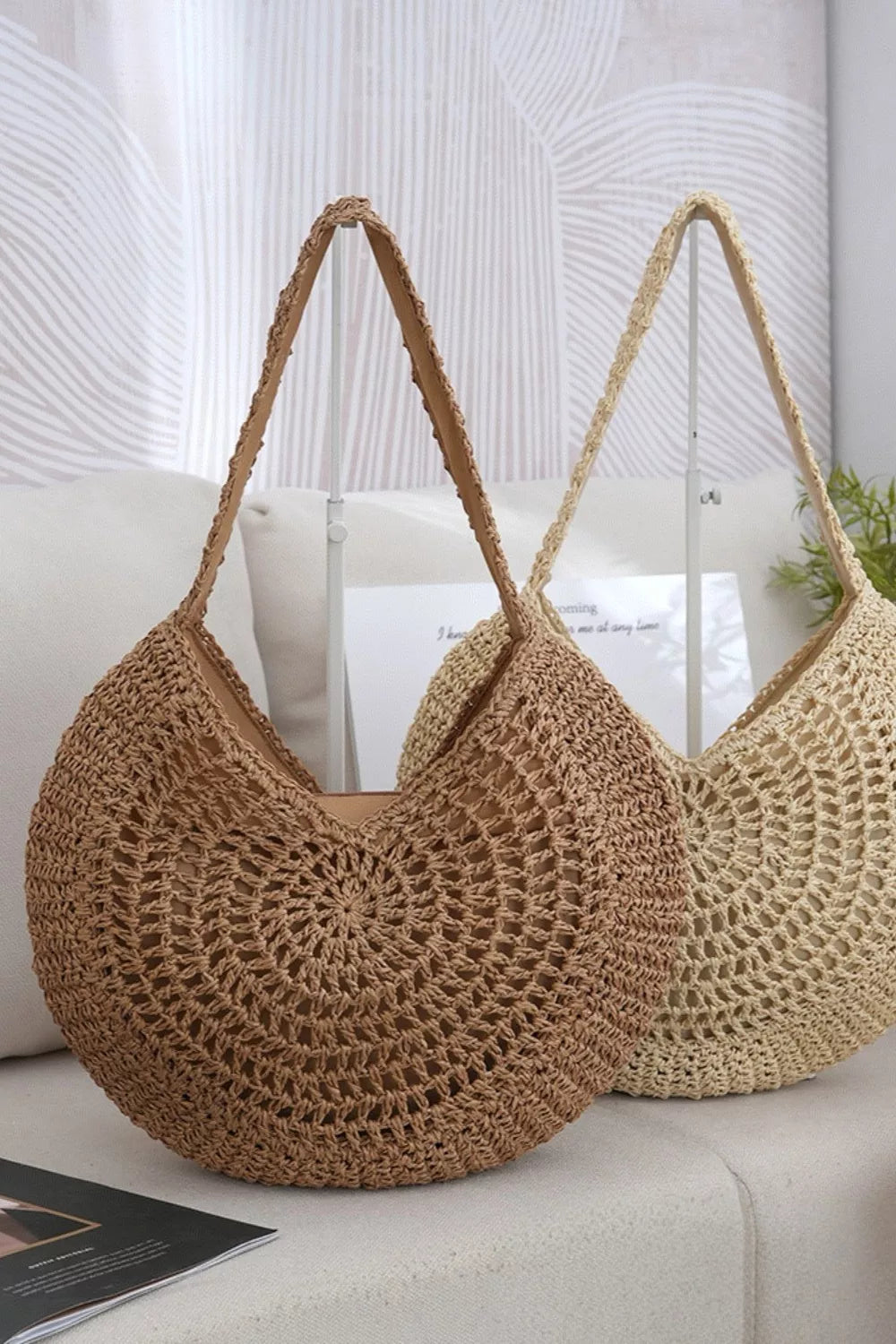 A medium tan round woven shoulder bag features an open crochet-style construction, rounded silhouette, and long matching shoulder strap.
