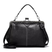 Medium black PU leather handbag with a structured silhouette, kiss-lock frame closure, top handle, detachable shoulder strap, and decorative trim.