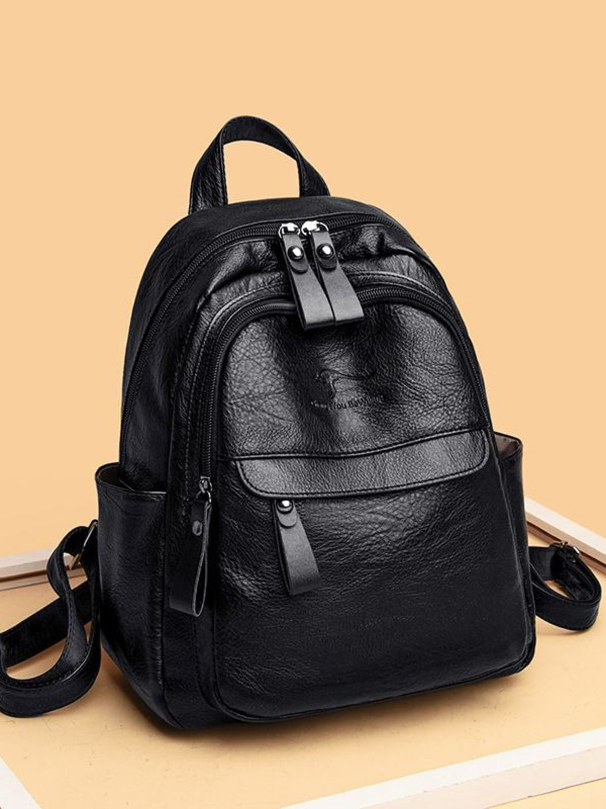 Black medium PU leather backpack with a structured silhouette, top handle, adjustable shoulder straps, multiple zippered compartments, and a front flap pocket.