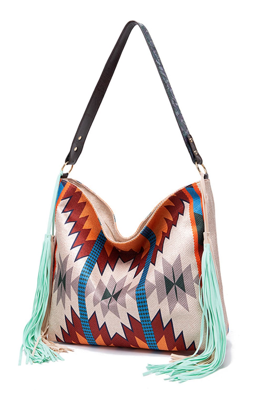 Oversize geometric canvas tote bag with a colorful zigzag pattern, long black shoulder strap, open top, and mint-green fringe detailing along the sides.