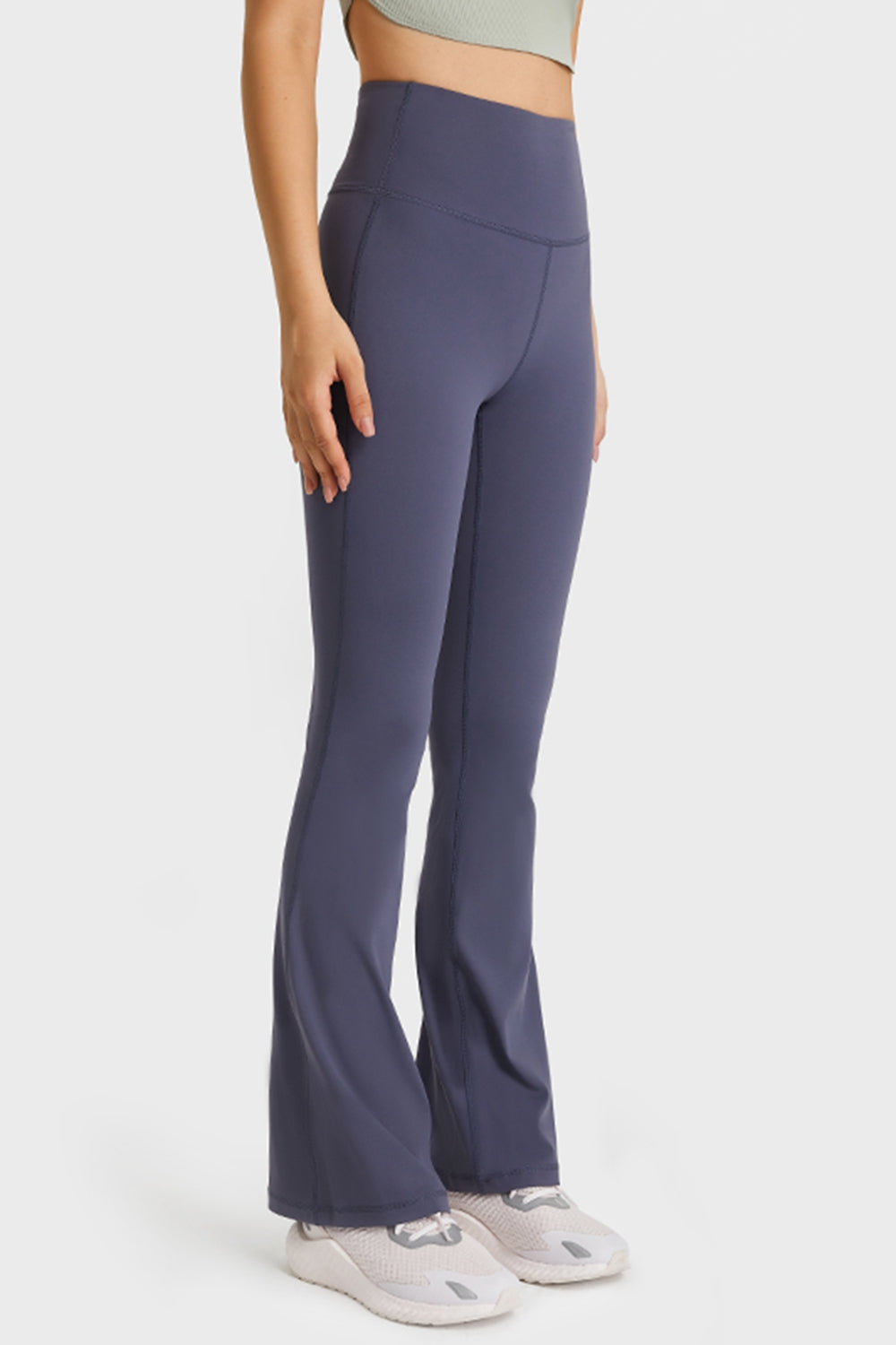 A model stands in dark purple elastic-waist flare yoga pants with a high-rise fit, smooth seamed construction, fitted hips and thighs, and long flared legs.