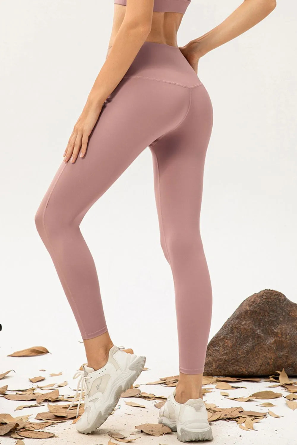 Model poses in mauve high-waist skinny active pants with a close-fitting ankle-length silhouette and visible curved seam construction.