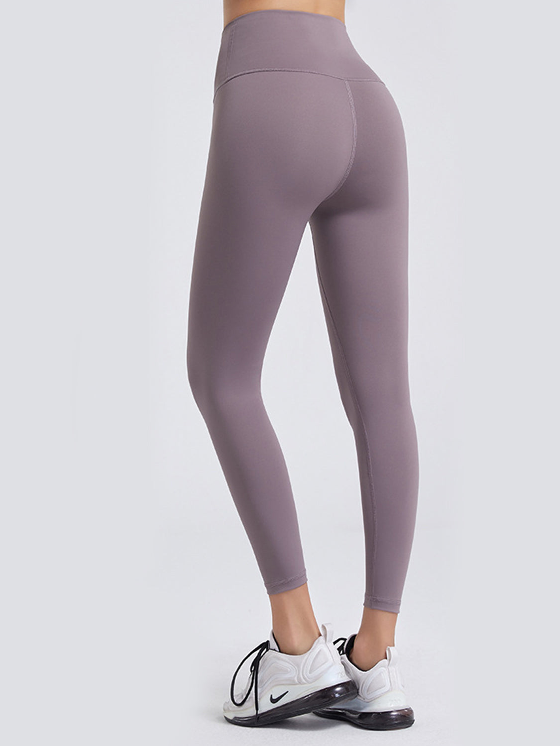 Model shown from the back in mauve wide waistband sports leggings with a high-rise fit, seamed construction, and sleek ankle-length silhouette.