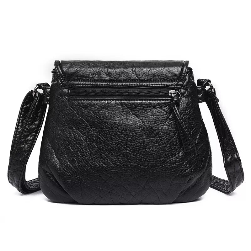 Small black PU leather crossbody bag with an adjustable strap, textured finish, top flap, and a front zippered pocket.