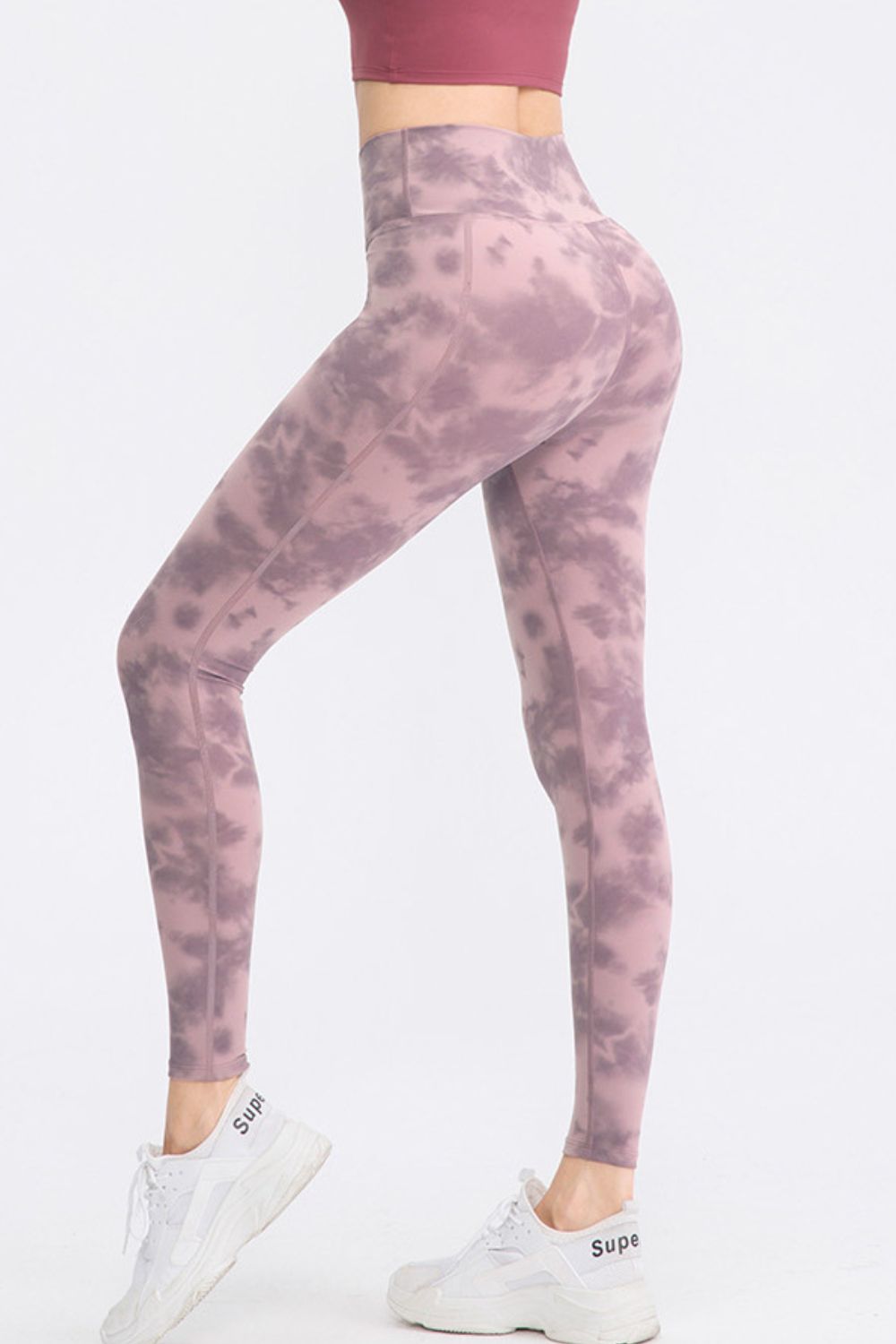 Model poses in mauve tie-dye long sports leggings with a wide waistband, slim-fit silhouette, and visible seaming.