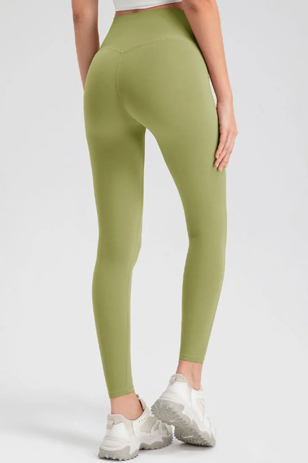 Model shown from behind in olive green high-waist skinny active pants with a smooth, stretch-fit silhouette, ankle-length legs, and visible seam construction.