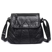 Small black PU leather crossbody bag with an adjustable strap, textured finish, stitched panel construction, flap closure, and front zip pocket.