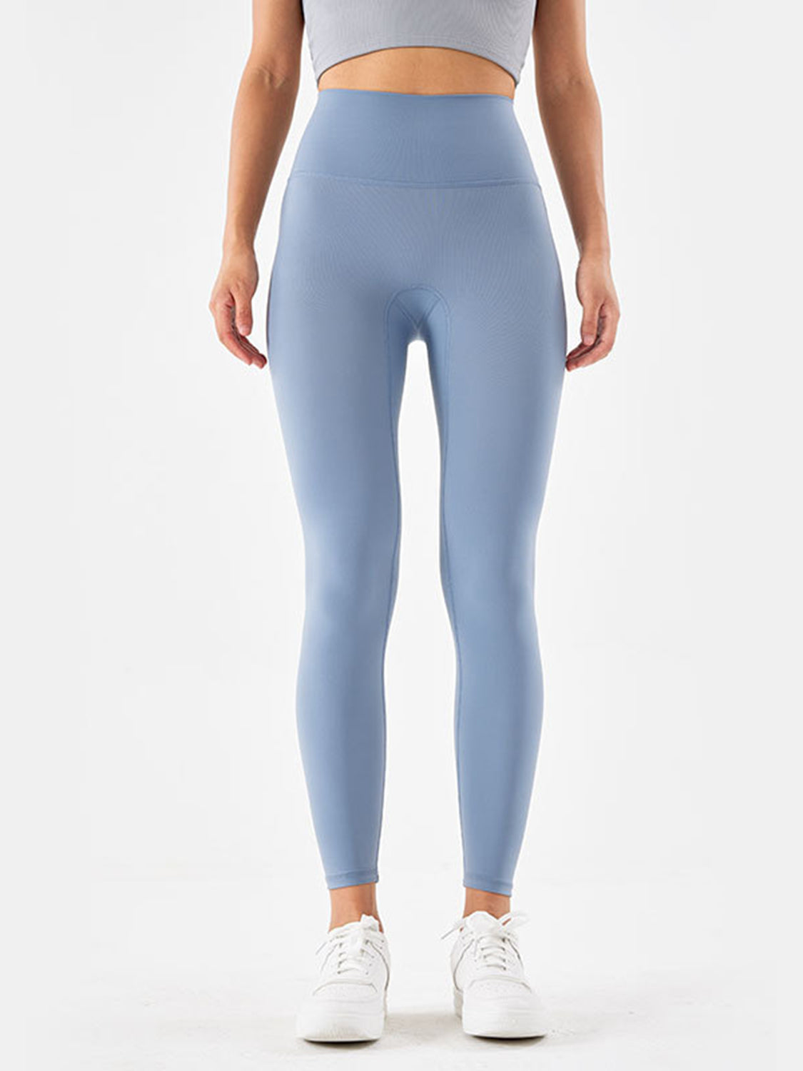 Model stands facing forward in light blue sports leggings with a wide high-rise waistband, smooth construction, and a fitted full-length silhouette.
