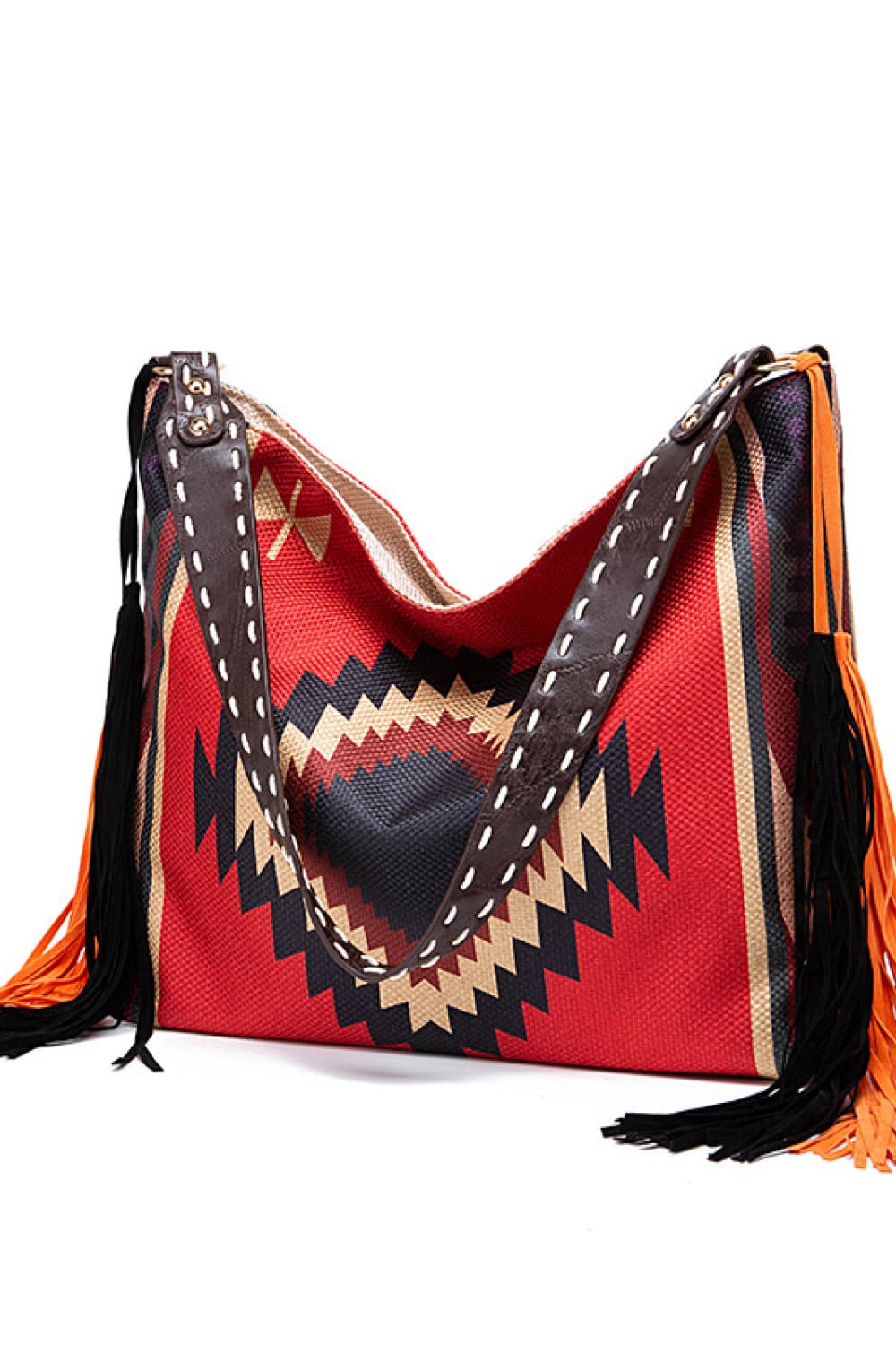Oversize geometric canvas tote bag in red, black, and cream with broad stitched handles, structured sides, and long black and orange fringe trim.
