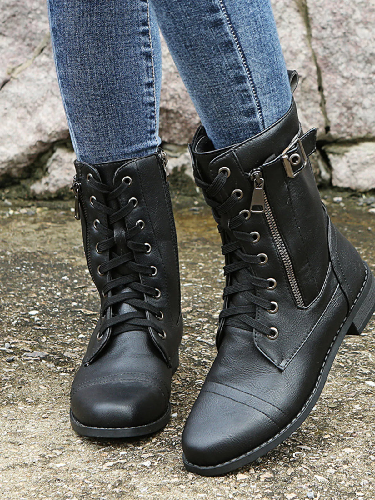 Model wearing black PU leather lace-up boots with side zippers, buckled ankle straps, rounded toes, and low block heels over blue jeans.