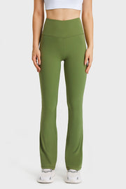 A model stands in olive green elastic-waist flare yoga pants with a high-rise fit, smooth stretch fabric, seam detailing, and long fitted-to-flared legs.
