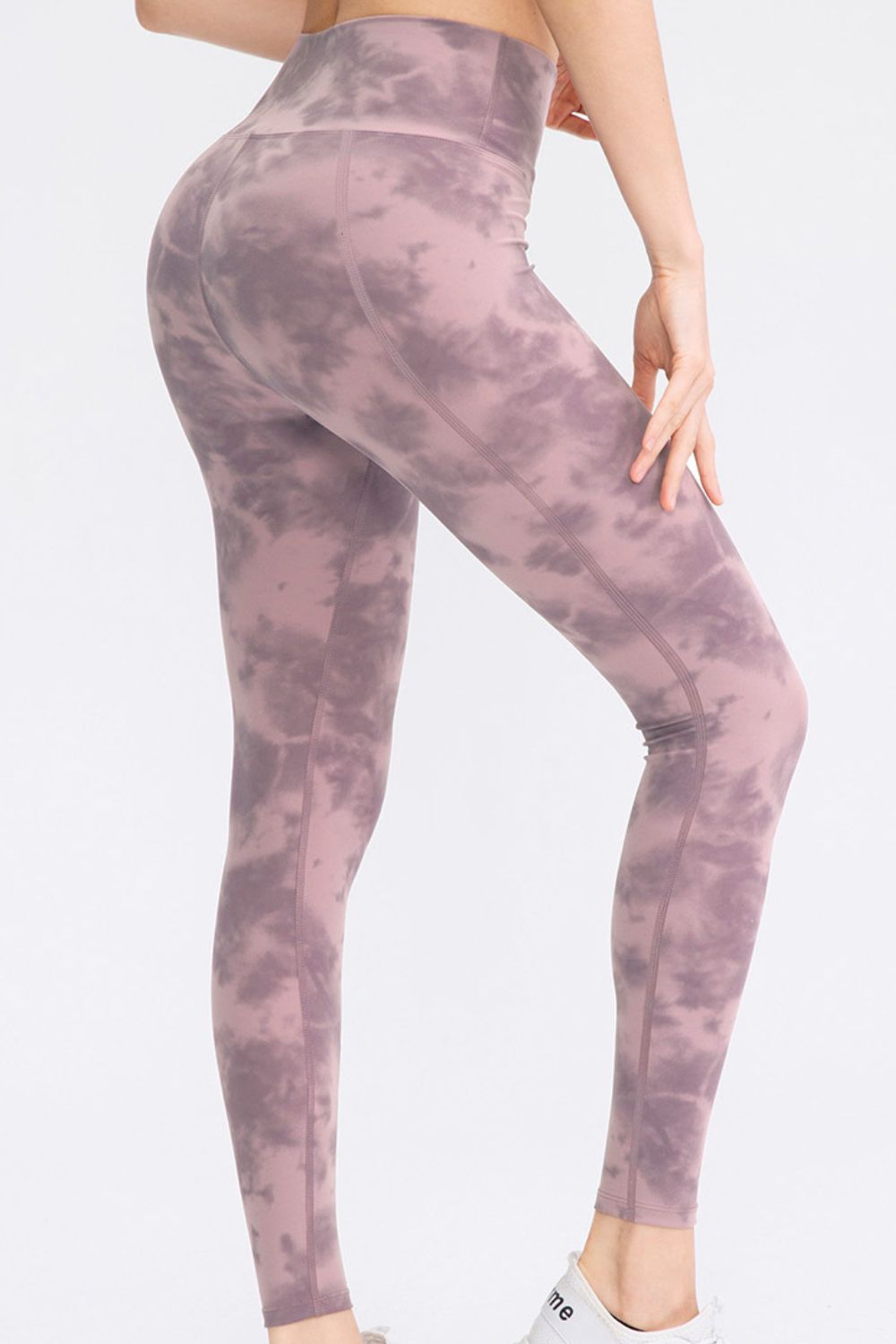 A model poses in mauve-purple tie-dye slim-fit long sports pants with a wide waistband, contoured seams, and a close-fitting ankle-length silhouette.