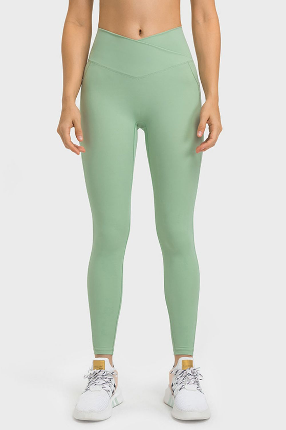 Model stands with hands at her sides wearing mint green, full-length yoga leggings with a flattering V-waist, smooth construction, and a close, stretchy silhouette.