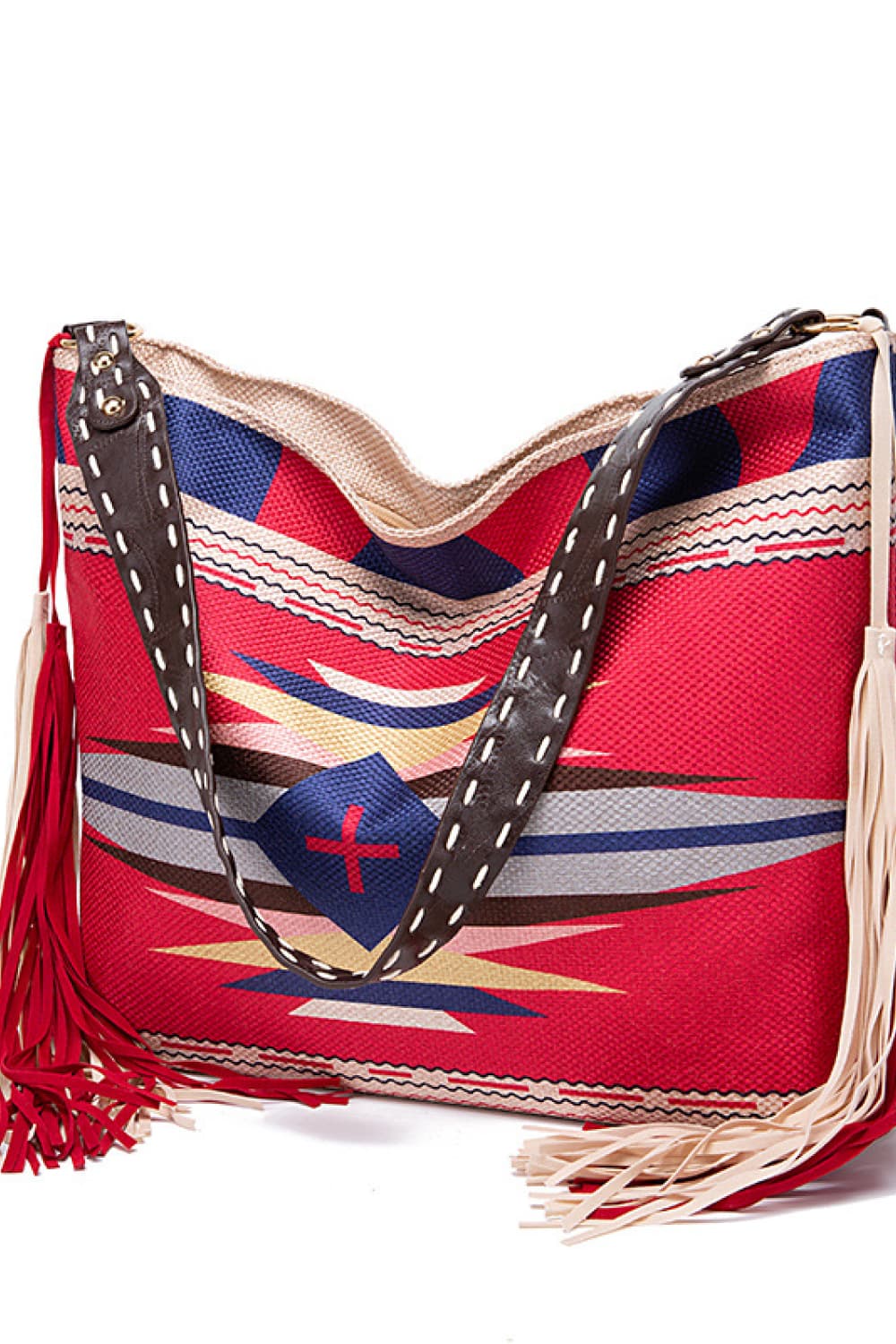 Oversize geometric canvas tote bag in red with navy, cream, and black patterned panels, dark stitched handles, and long fringe detailing.