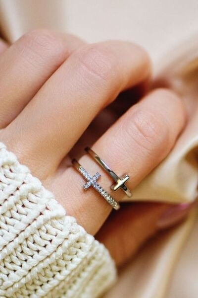 A close view of a hand wearing a slim 925 sterling silver cross ring with sparkling zircon accents and a polished adjustable band.