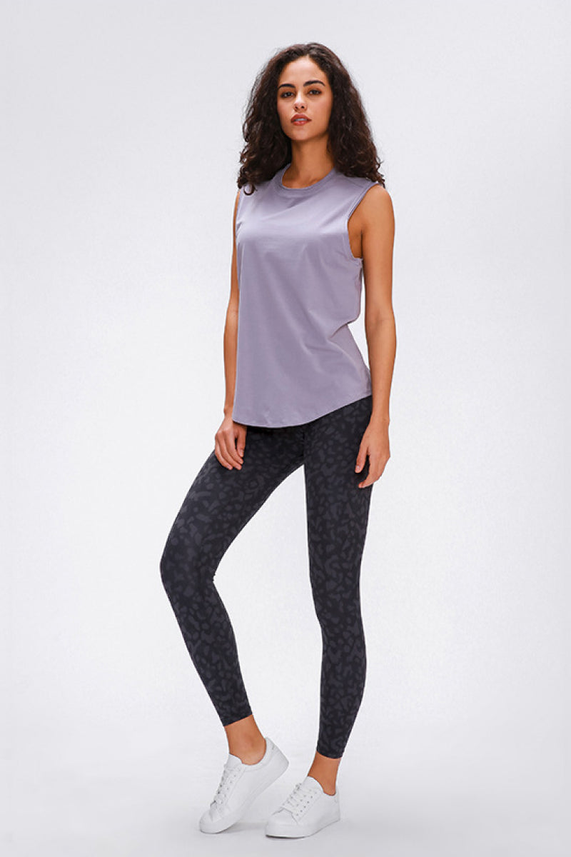 A model poses in dark charcoal sports leggings with a subtle tonal pattern, fitted full-length silhouette, wide seamless band waist, and one leg bent.