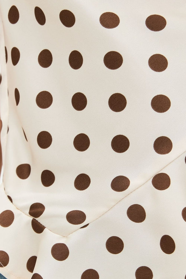 Crisscross ruffled hem polka dot cami with tied, ruched, and backless design.