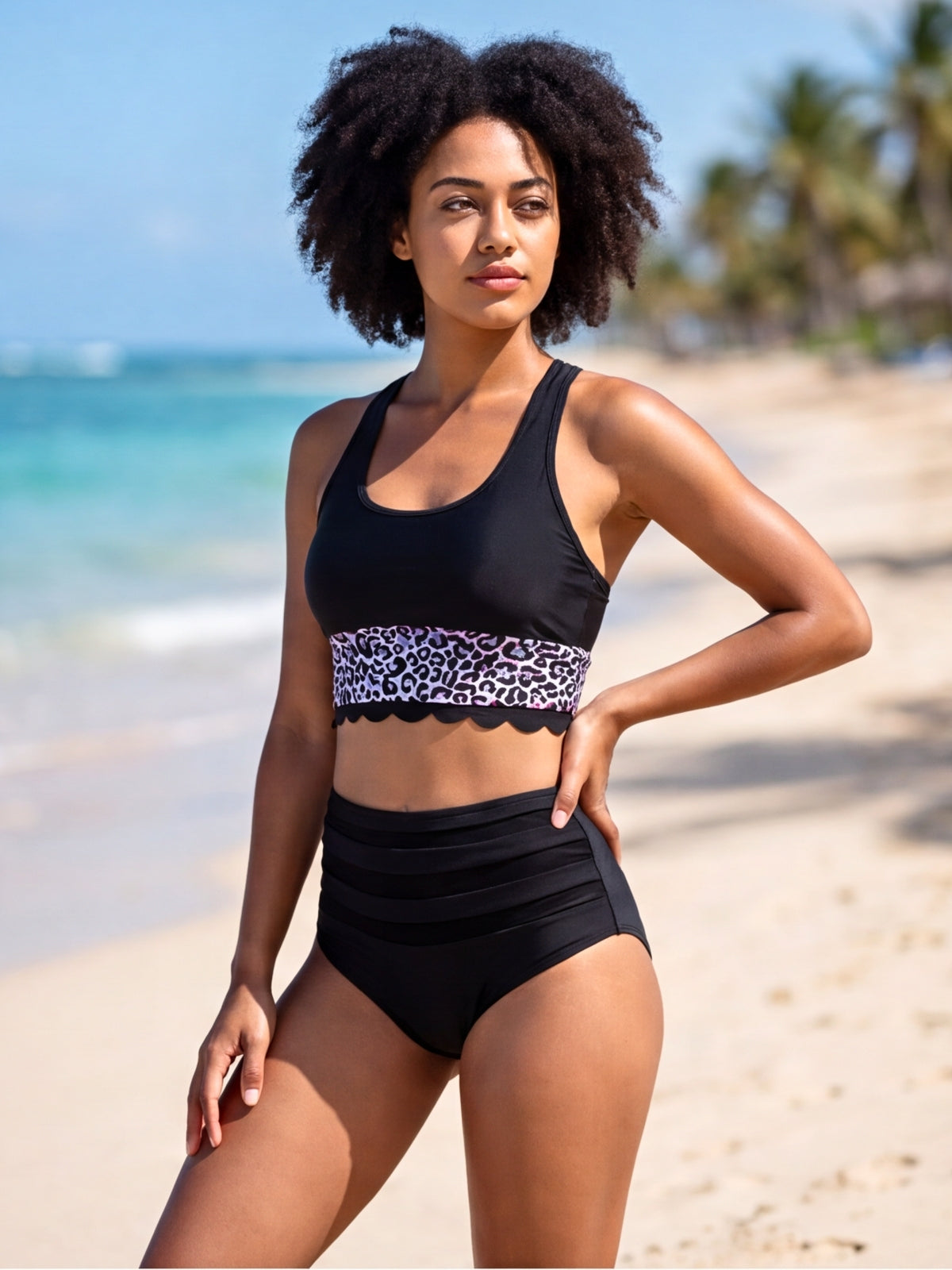 A model poses in a black two-piece bikini with wide straps, a leopard-print band, scalloped trim, and high-waisted ruched bottoms.