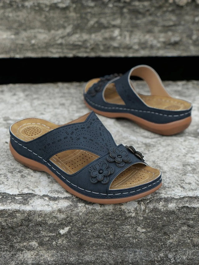 Open-toe flat sandals with cutout flower design.