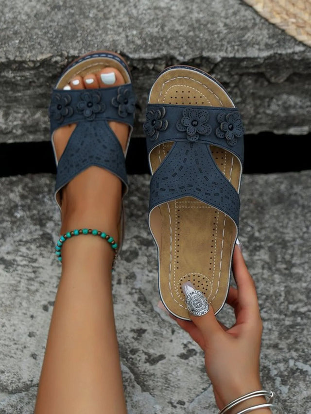 Open-toe flat sandals with cutout flower design.