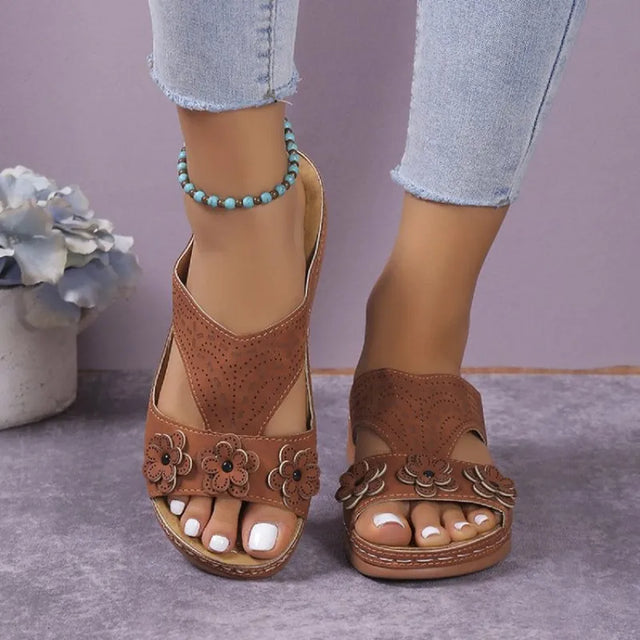 Open-toe flat sandals with cutout flower design.