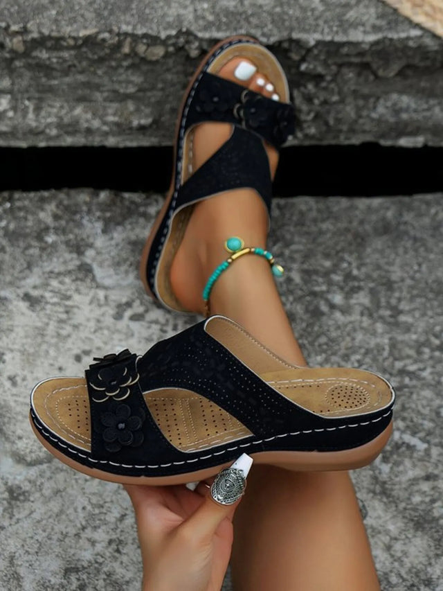 Open-toe flat sandals with cutout flower design.