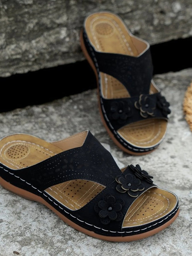 Open-toe flat sandals with cutout flower design.