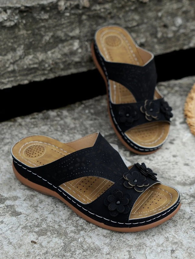 Open-toe flat sandals with cutout flower design.