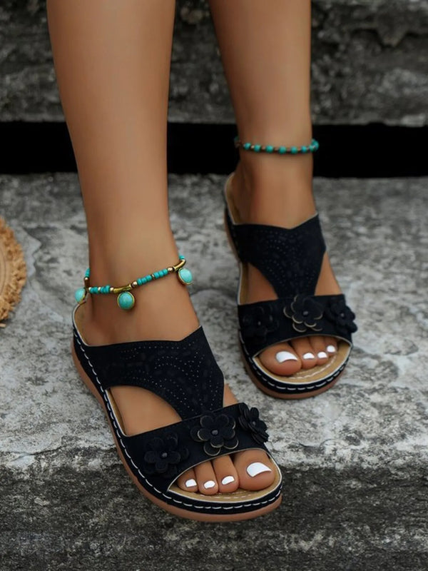 Open-toe flat sandals with cutout flower design.