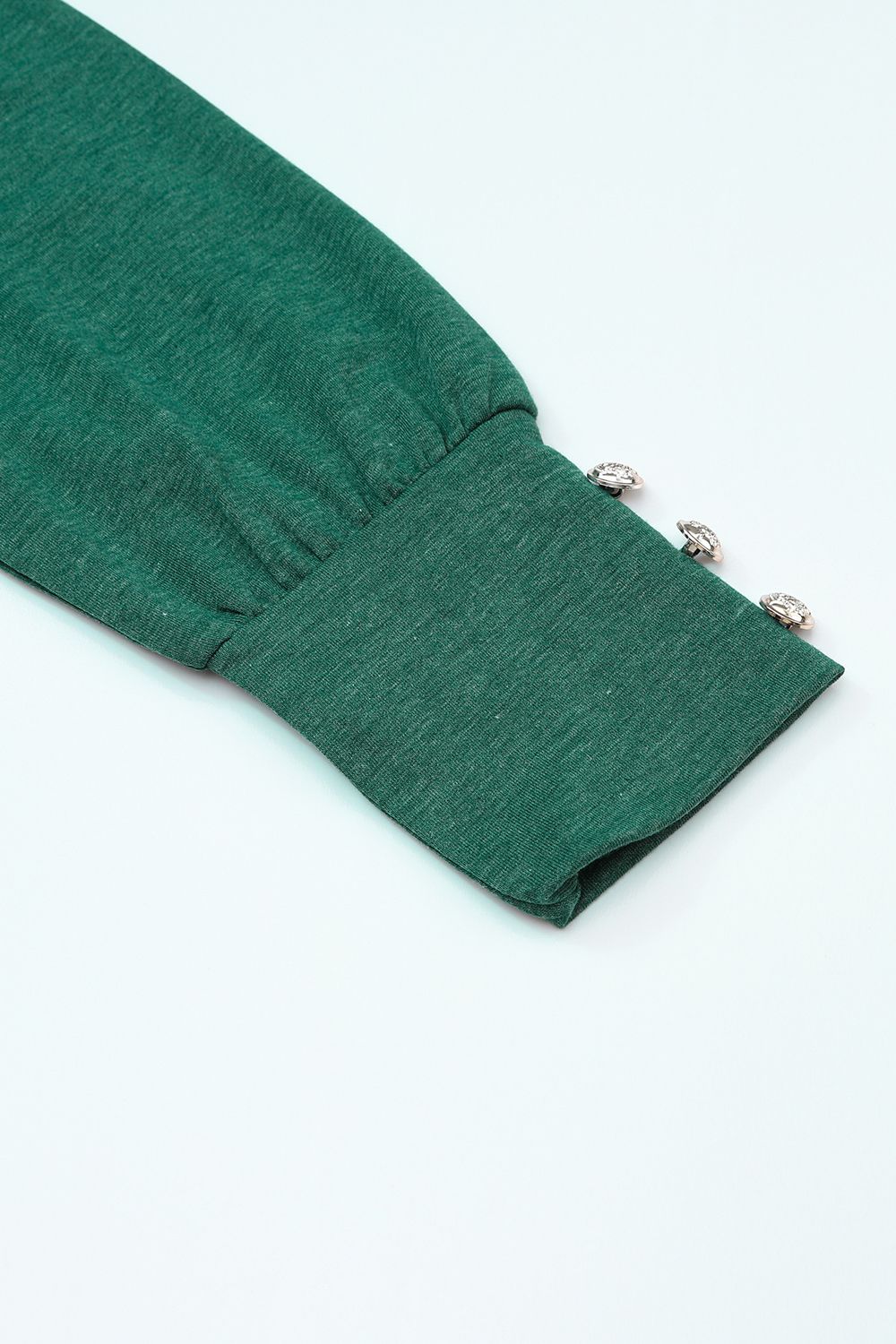Cutout round neck long sleeve top with decorative buttons.