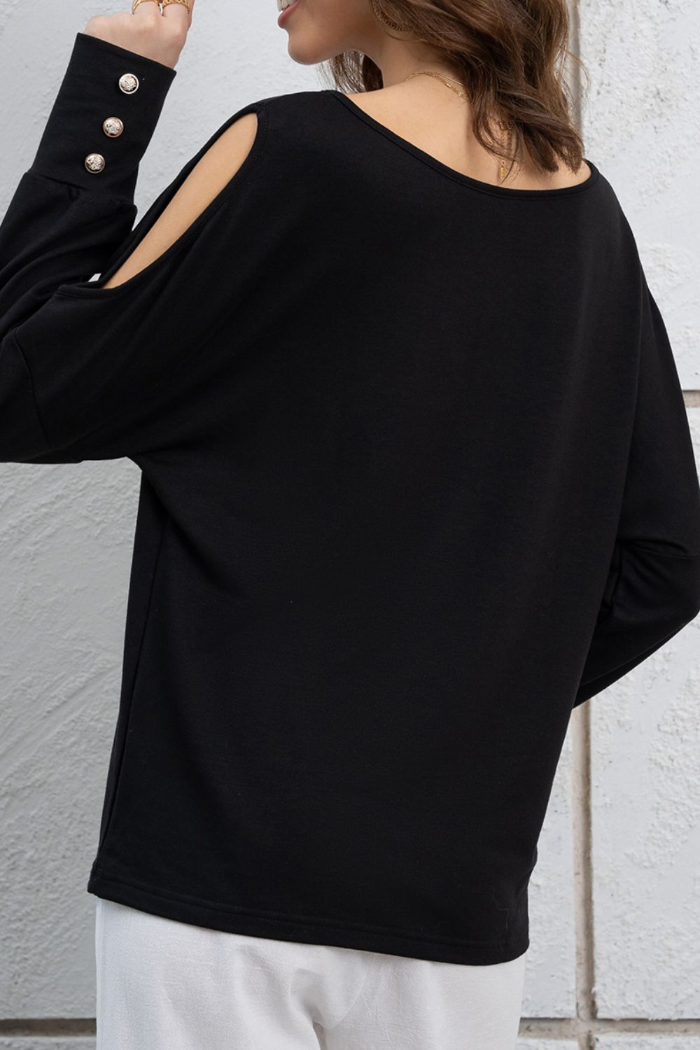 Cutout round neck long sleeve top with decorative buttons.