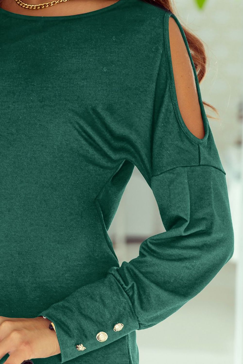 Cutout round neck long sleeve top with decorative buttons.