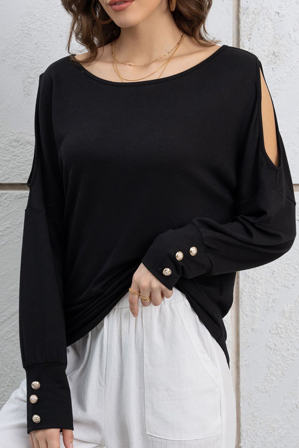 Cutout round neck long sleeve top with decorative buttons.