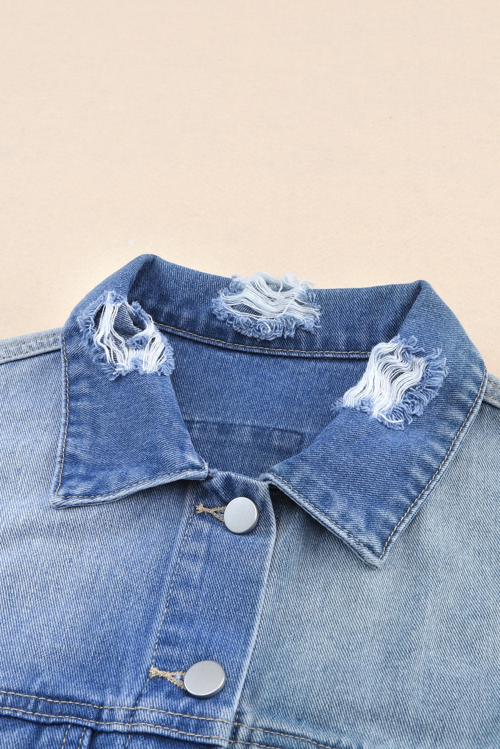 Distressed button up drop shoulder denim jacket with raw hem and pockets.
