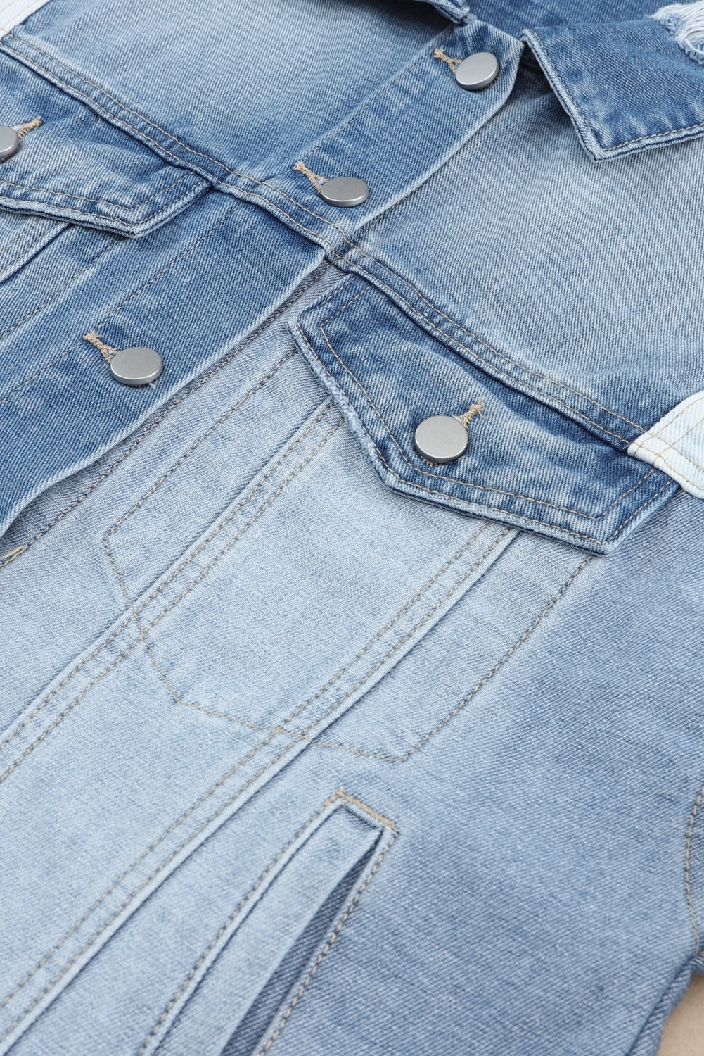 Distressed button up drop shoulder denim jacket with raw hem and pockets.