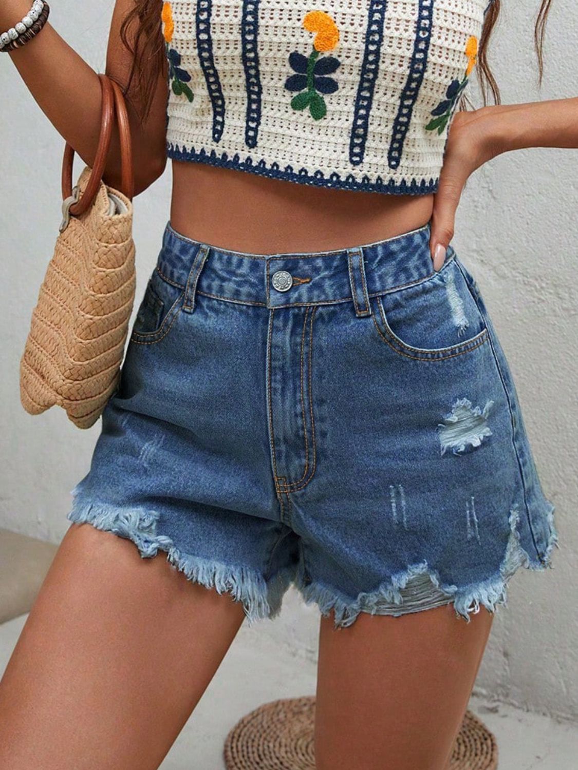 Distressed raw hem denim shorts with buttons and pockets.