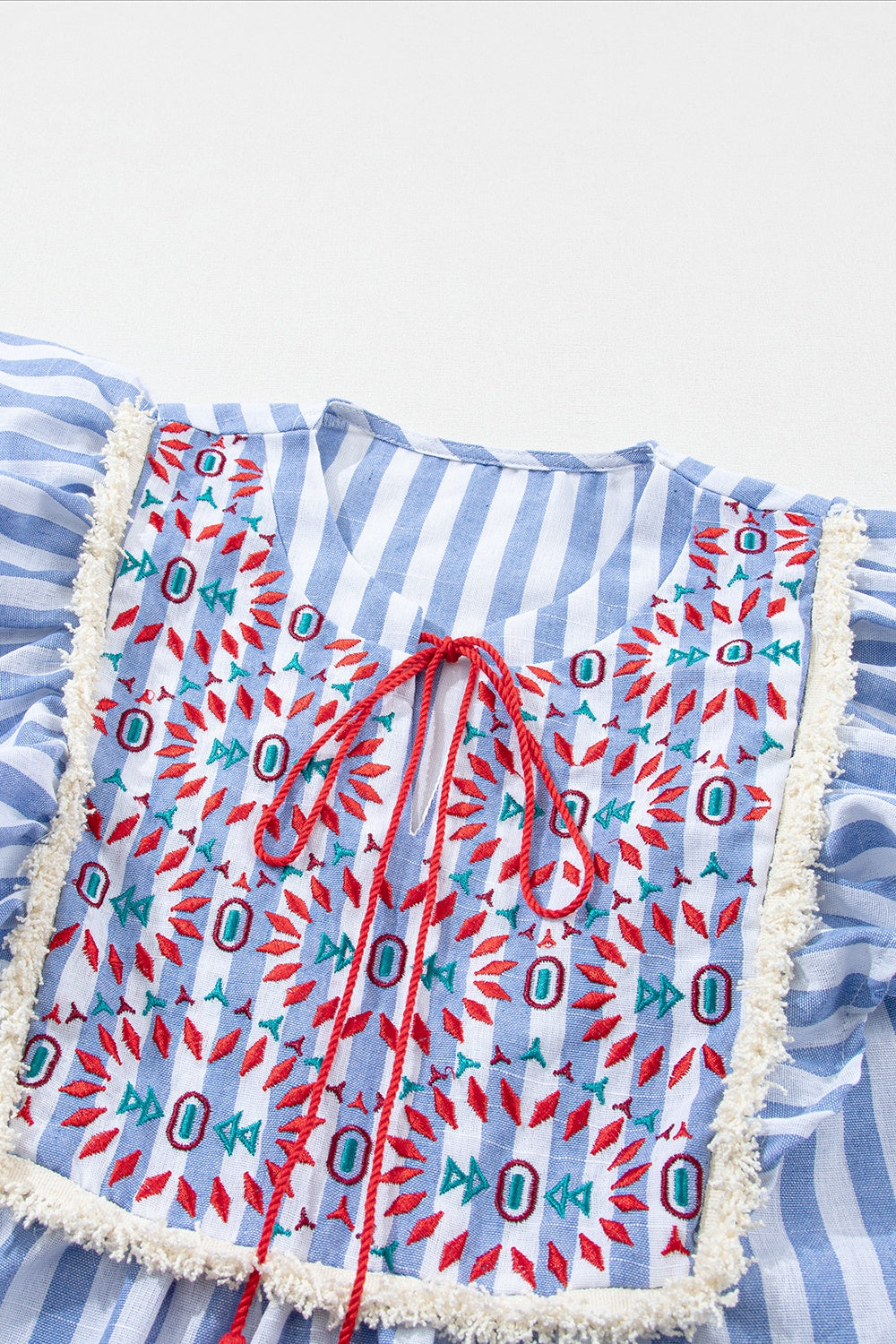 Embroidered tassel striped tie neck blouse with ruffles.