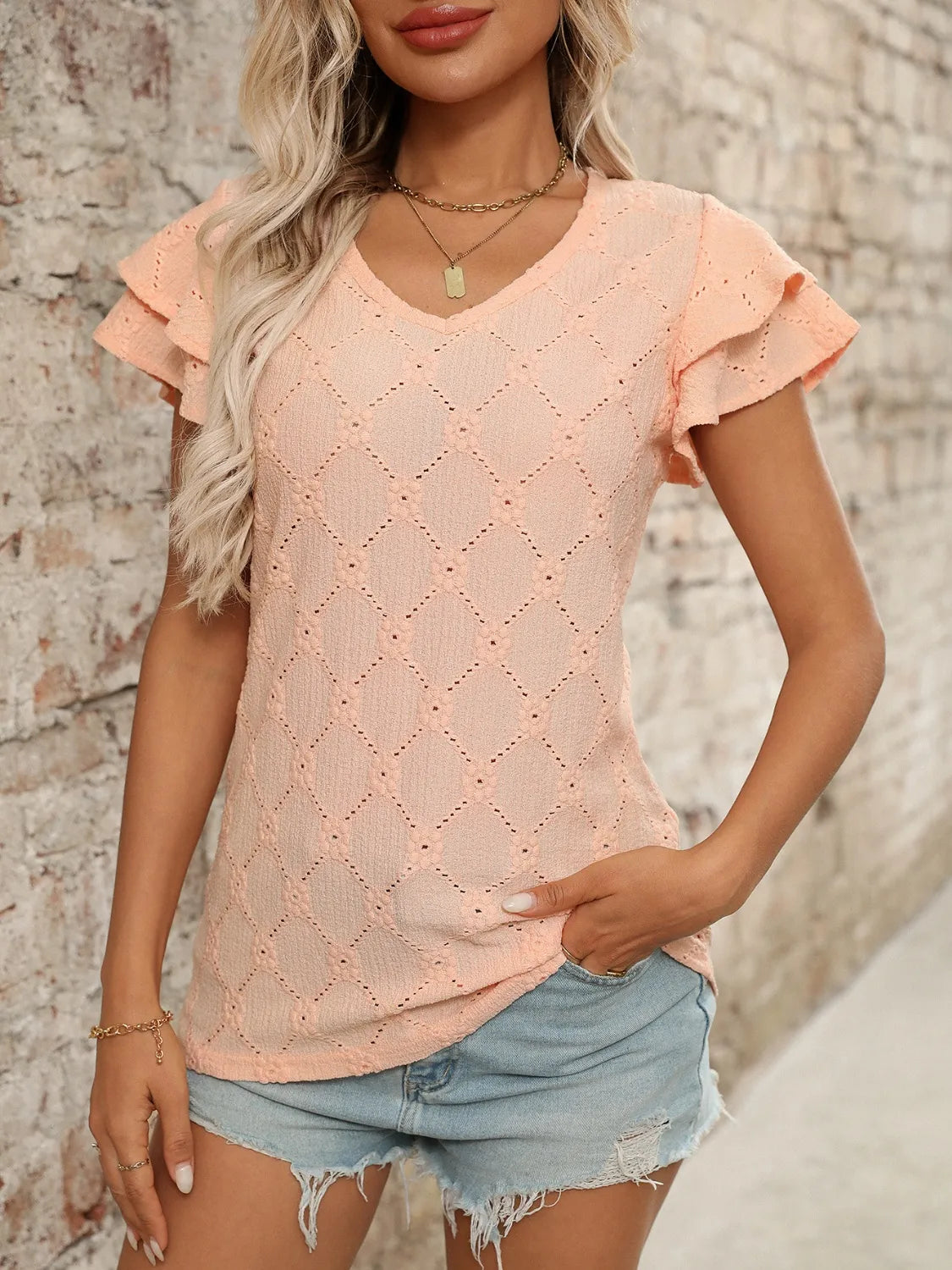 Eyelet V-neck ruffled cap sleeve top with decorative buttons and lace.
